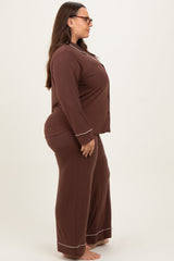 woman wearing a brown long sleeve plus size pajamas set with contrasting white piping, standing sideways