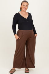 woman wearing a black long sleeve henley top and brown wide leg maternity pants with pockets