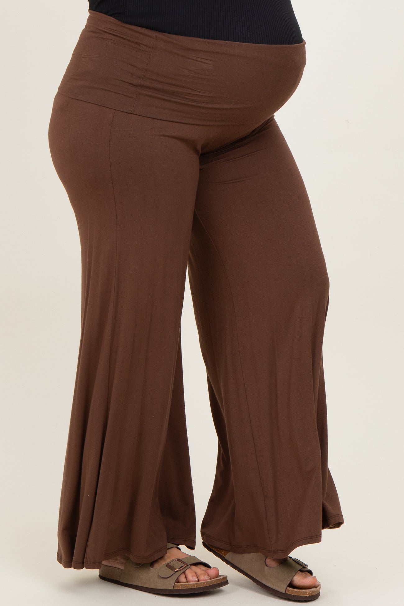 woman wearing brown maternity plus flowy pants, showcasing a visible baby bump