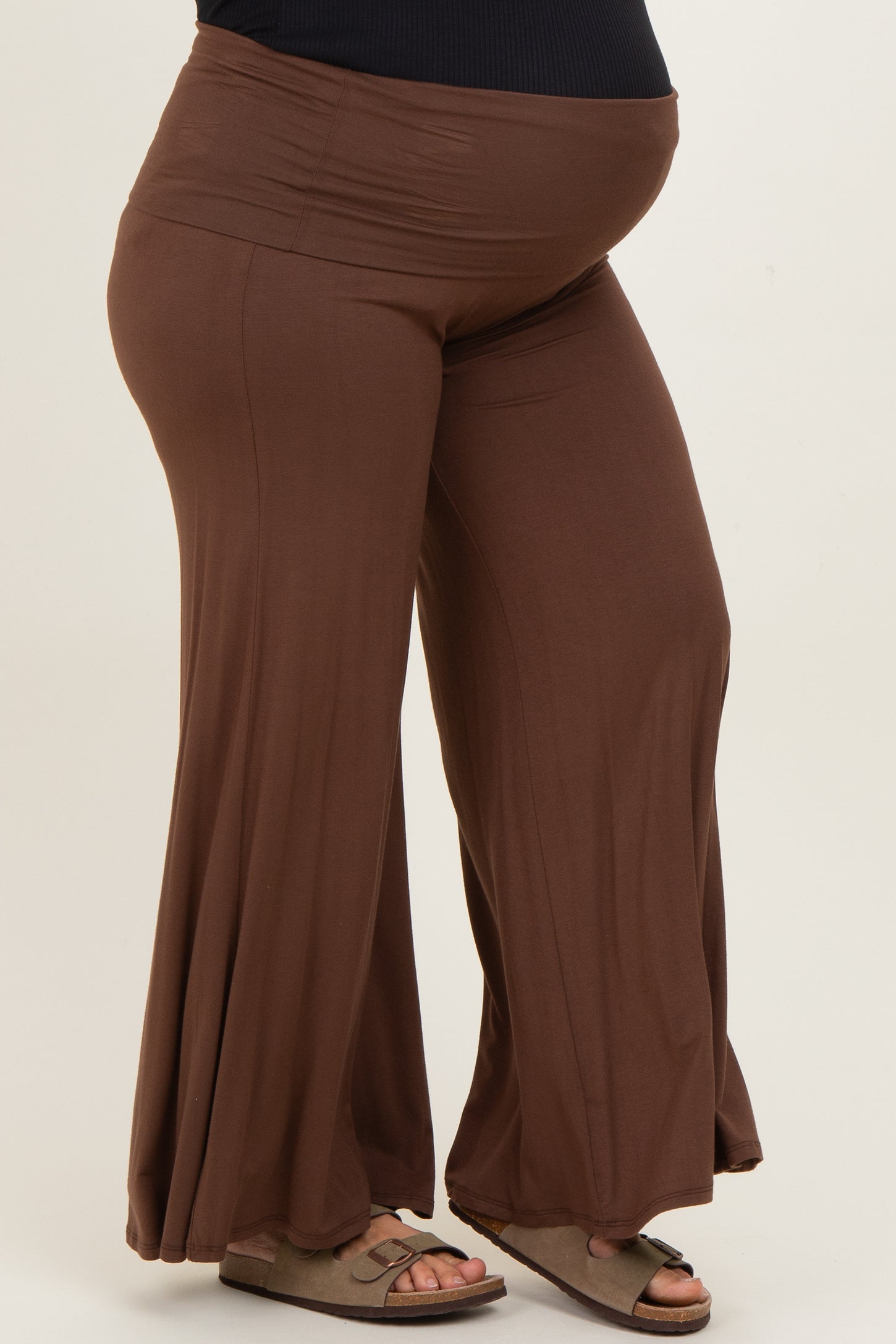 woman wearing brown maternity plus flowy pants, showcasing a visible baby bump