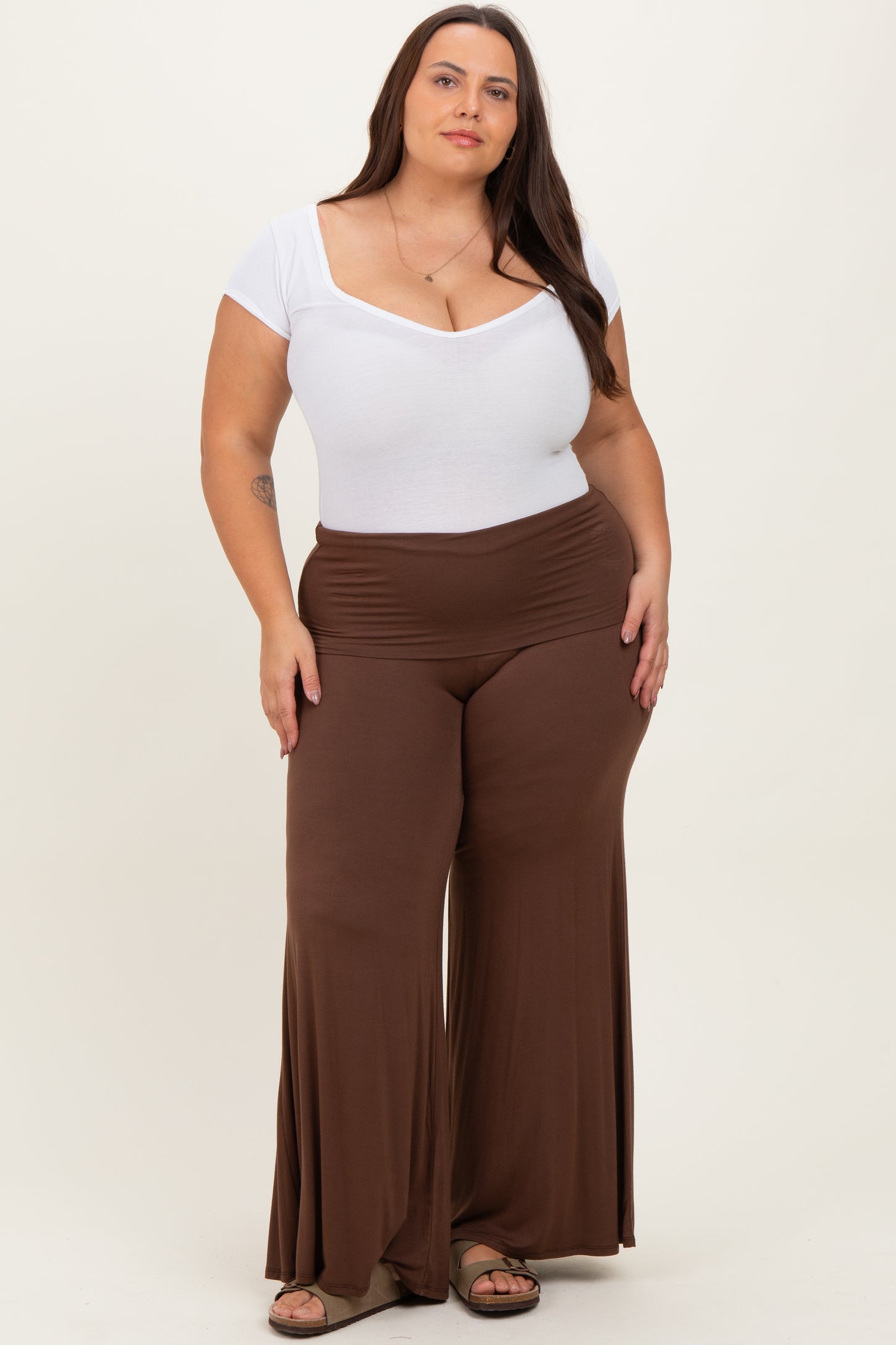 woman wearing a white short sleeve bodysuit and brown wide-leg pants