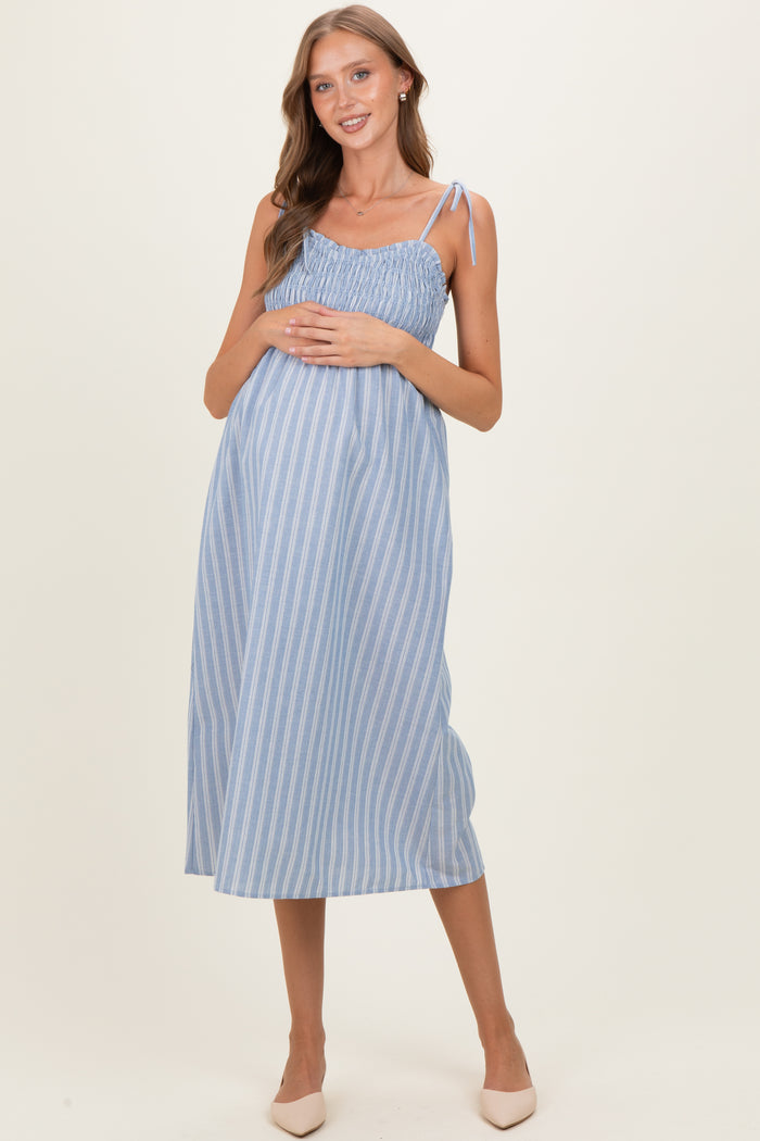 woman wearing a light blue striped maternity dress with adjustable tie straps and a visible baby bump