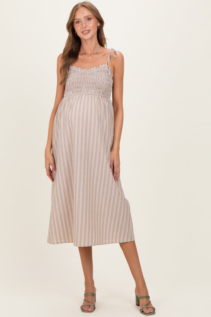 woman wearing a striped beige maternity dress with adjustable straps and a visible baby bump