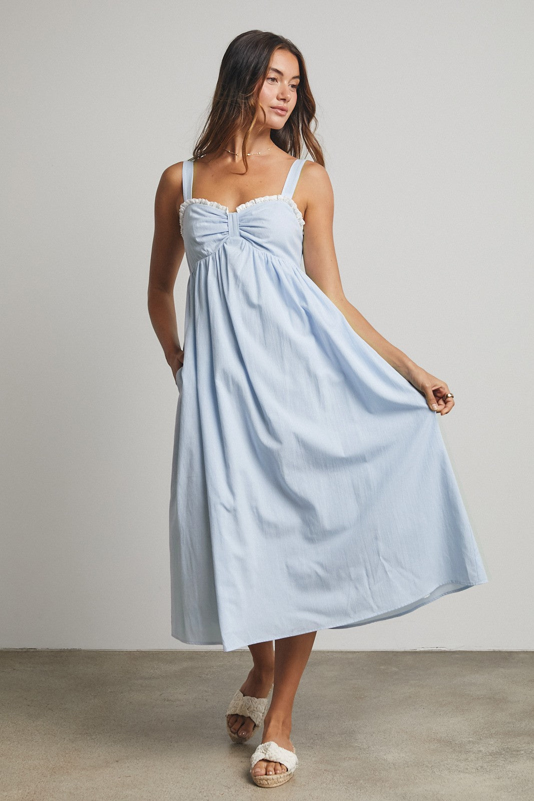 woman wearing a light blue sleeveless maxi dress with a gathered bodice and flowy skirt