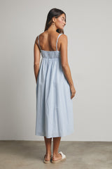 woman wearing a light blue sleeveless midi dress with smocked back and standing backwards