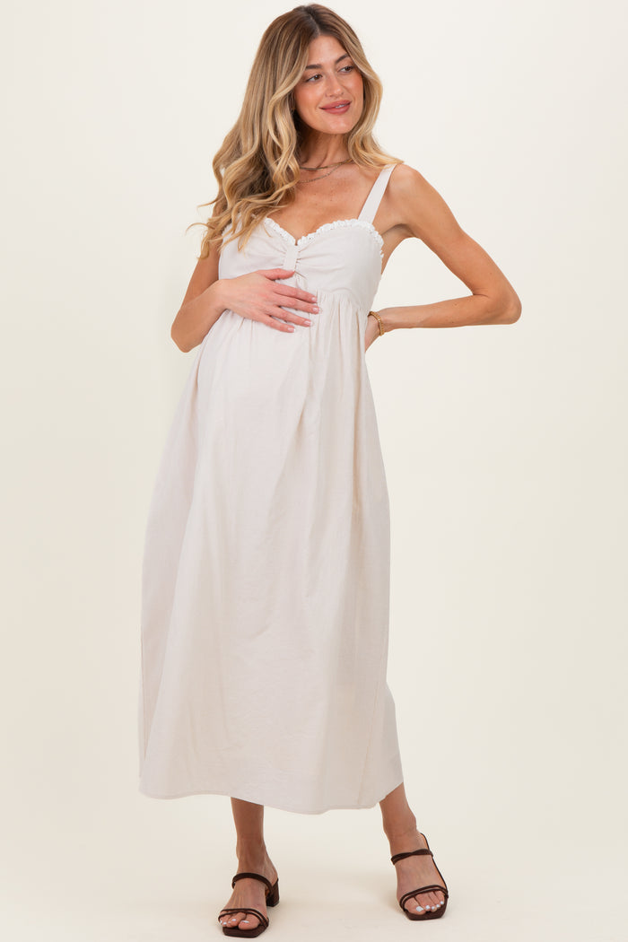 woman wearing a light pink maternity maxi dress with a button detail and holding her baby bump