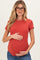 woman wearing a rust short sleeve maternity top and holding her baby bump