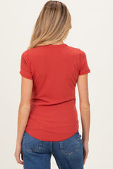 woman wearing a rust red short sleeve maternity top viewed from the back with casual blue jeans