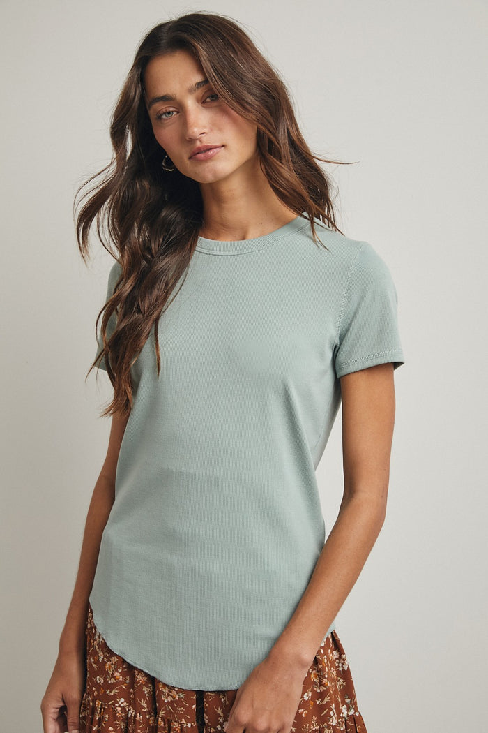 woman wearing a mint green short sleeve ribbed top with a round neckline, paired with a floral skirt