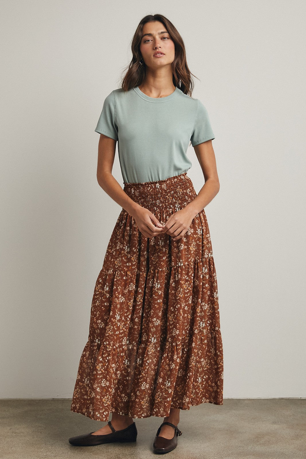 woman wearing a light green short sleeve top and a brown floral maxi skirt, styled casually