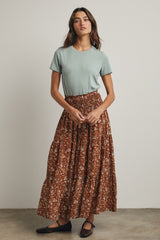 woman wearing a light green short sleeve top and a brown floral maxi skirt, styled casually