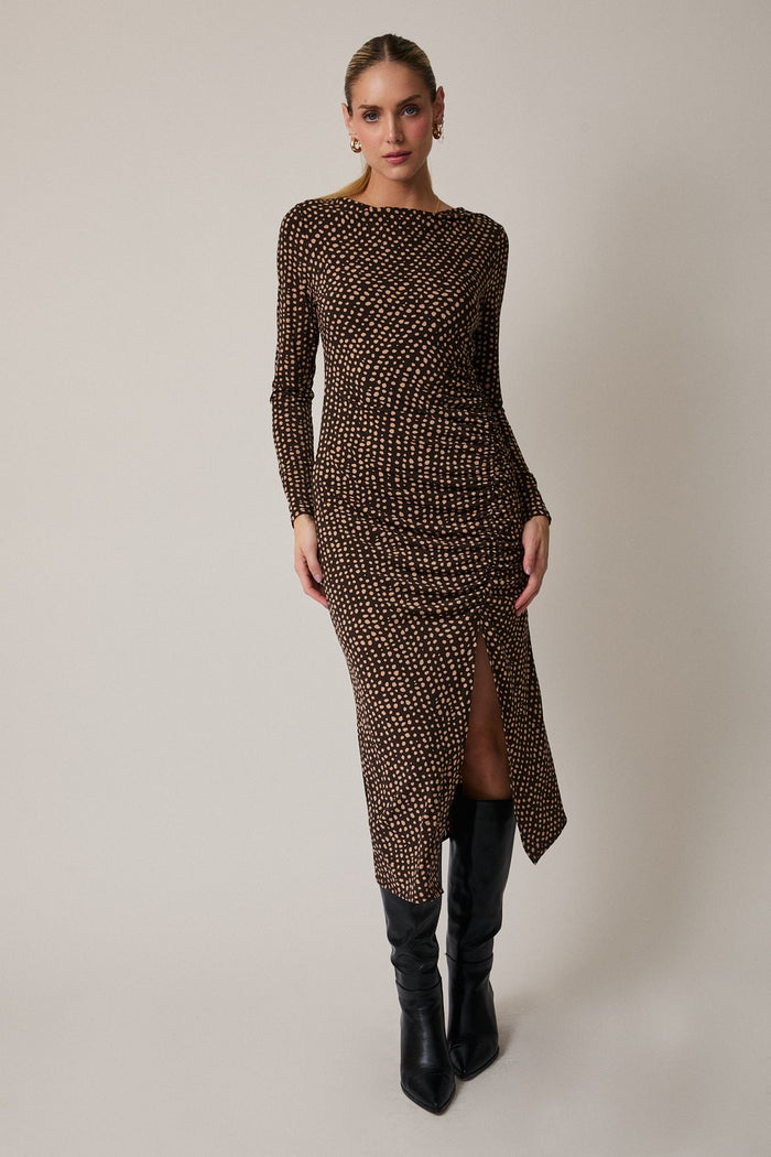 woman wearing a brown patterned long sleeve dress with a side slit and black knee-high boots
