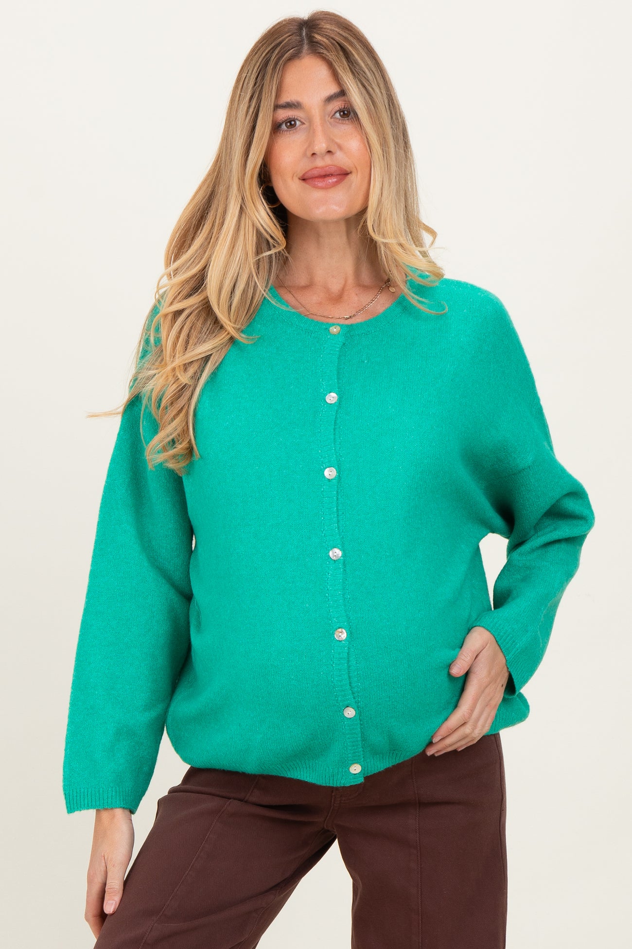 woman wearing a bright green maternity cardigan with buttons and a visible baby bump