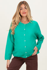 woman wearing a bright green maternity cardigan with buttons and a visible baby bump