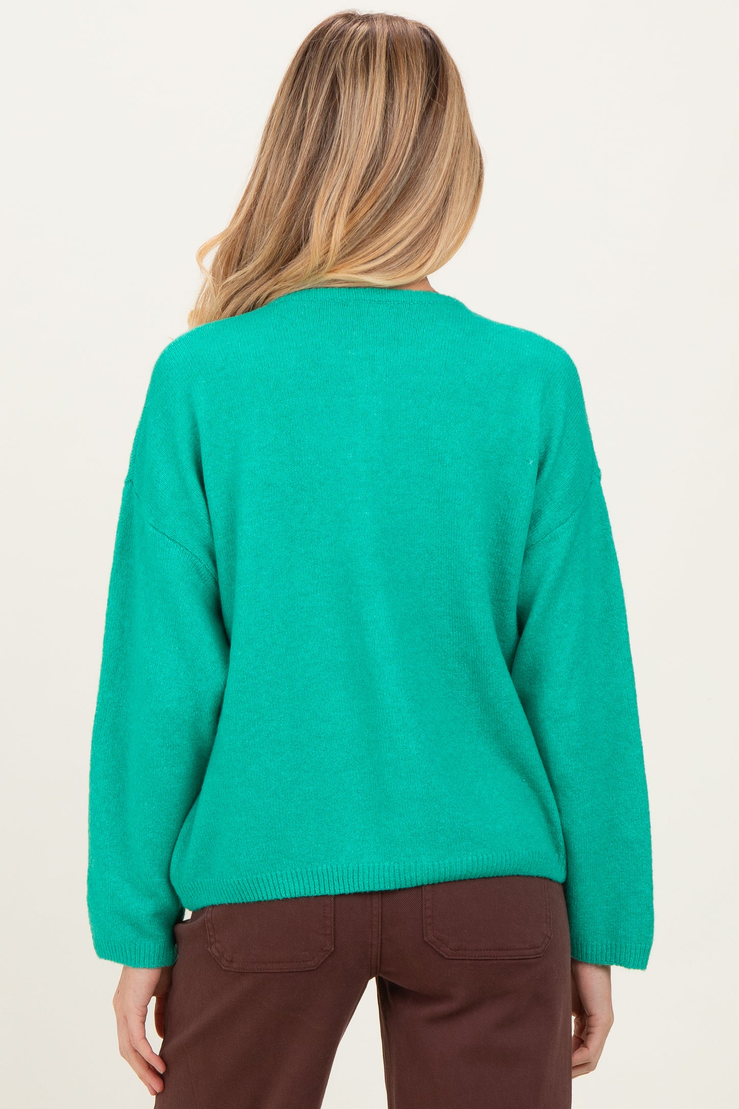 woman wearing a vibrant green oversized maternity sweater, seen from the back