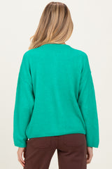 woman wearing a vibrant green oversized maternity sweater, seen from the back