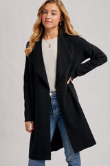 woman wearing a black long cardigan over a light gray sweater and blue jeans