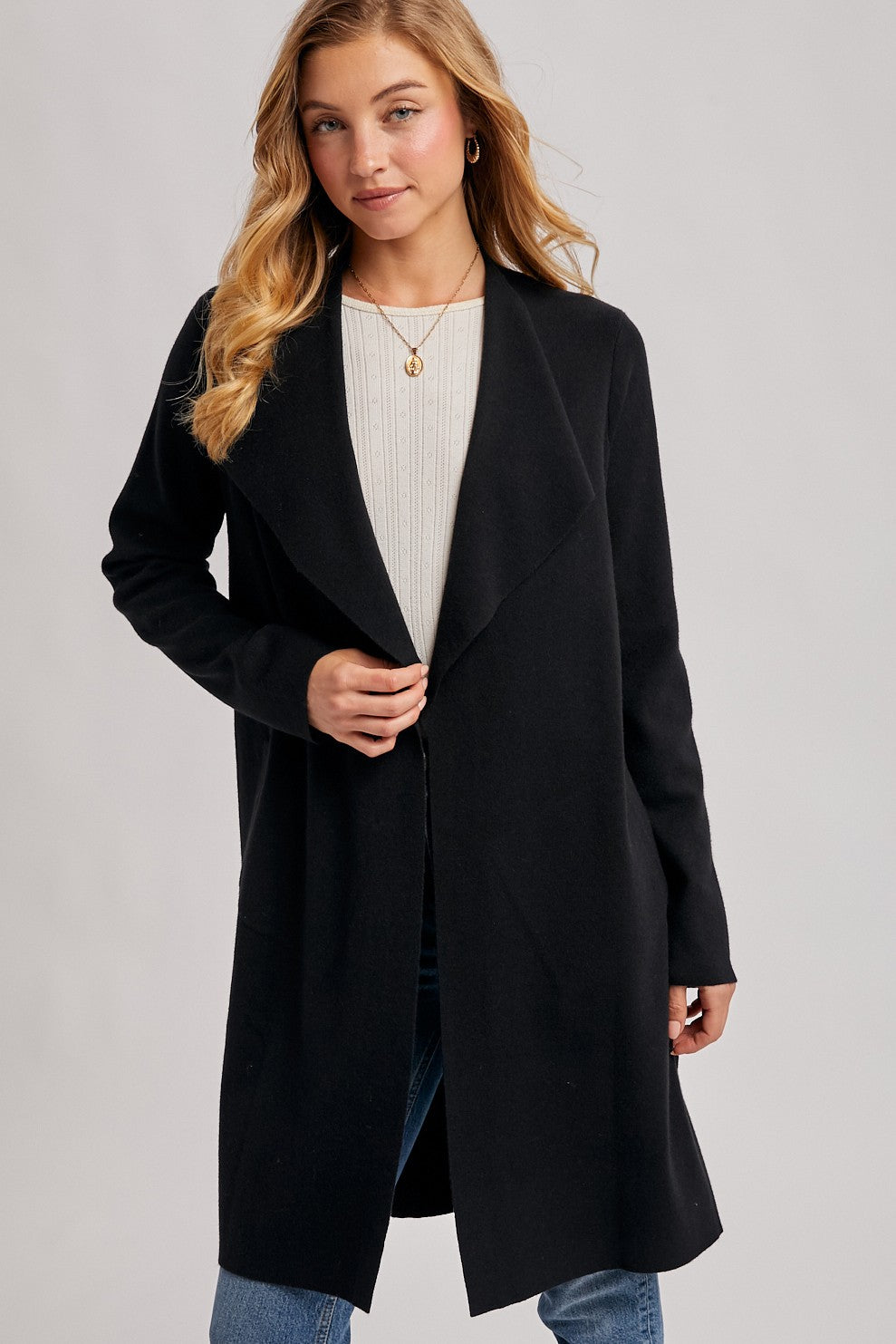 woman wearing a black long cardigan over a light sweater and blue jeans