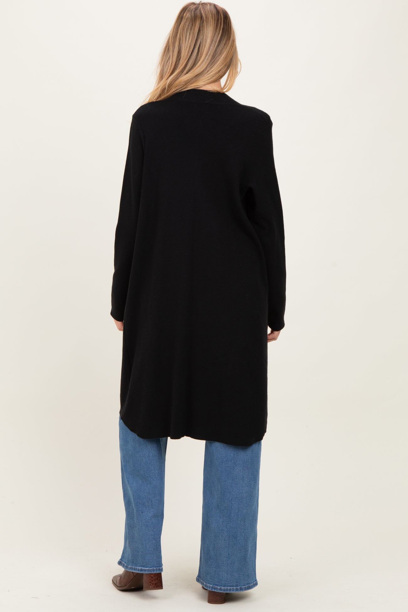 woman wearing a long black maternity cardigan with a relaxed fit, shown from the back, paired with light blue jeans