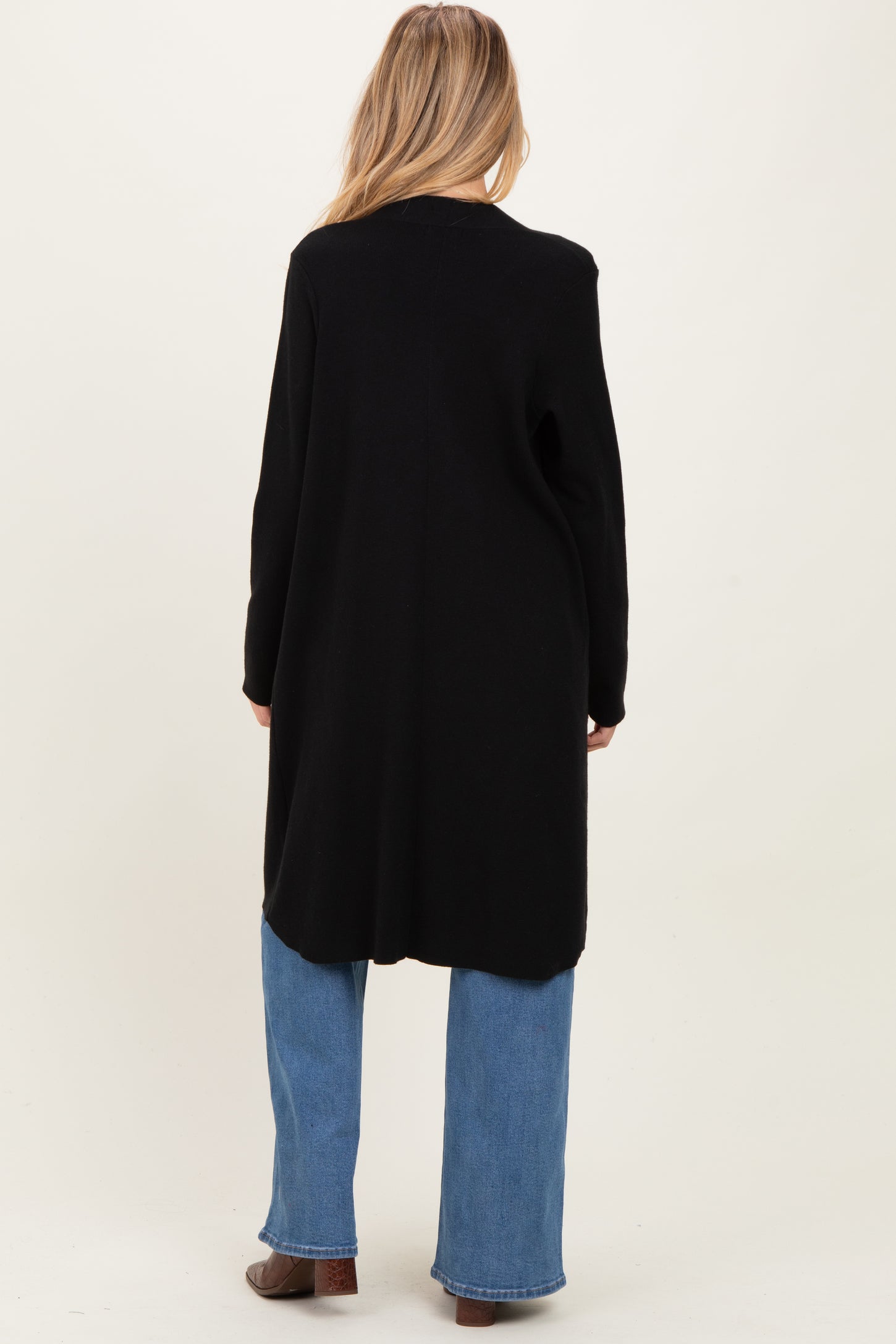 woman wearing a long black maternity cardigan with a relaxed fit, shown from the back, paired with light blue jeans