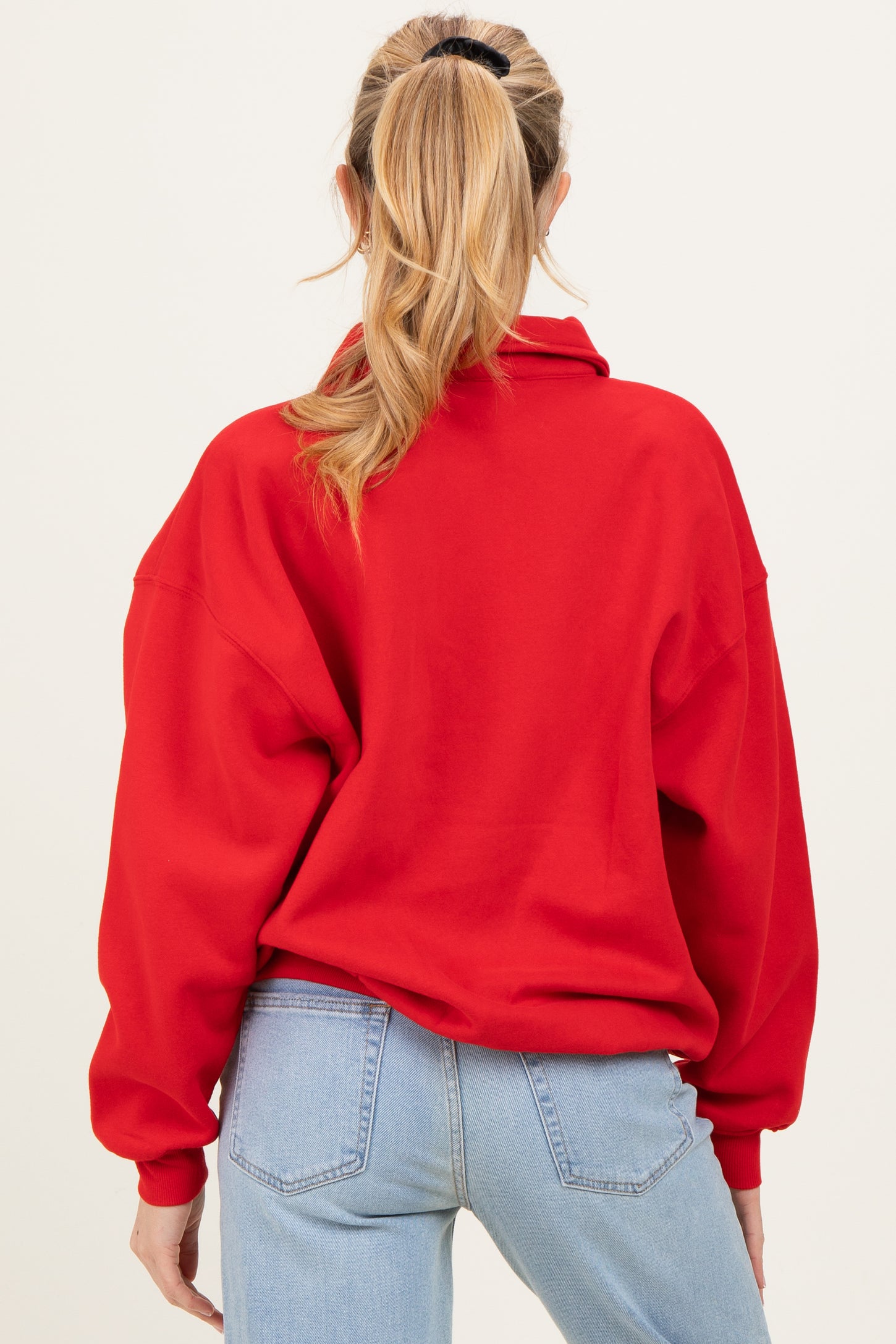woman wearing a red oversized maternity sweatshirt with a high collar and long sleeves