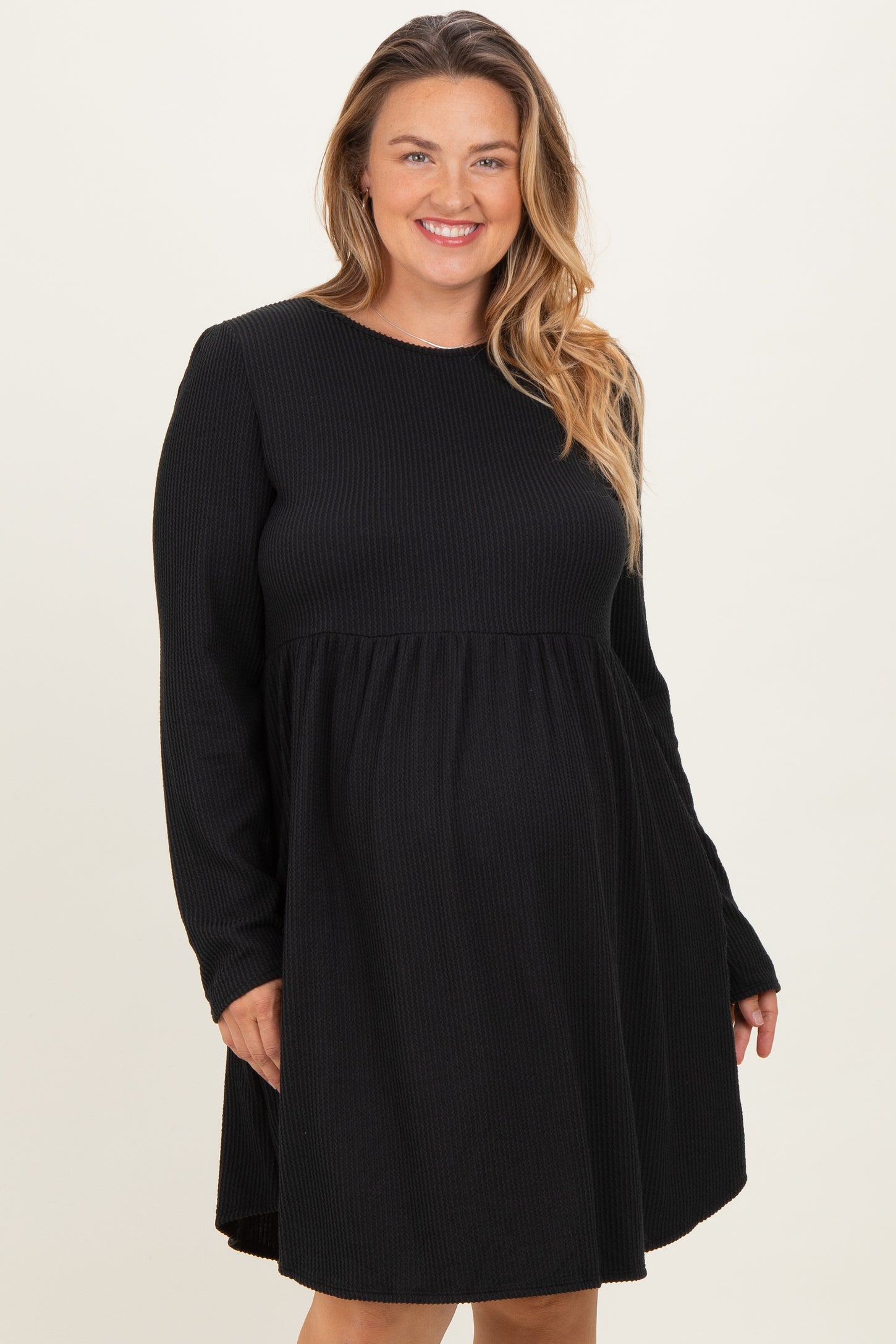 woman wearing a black long sleeve maternity dress with a flowy silhouette and a visible baby bump