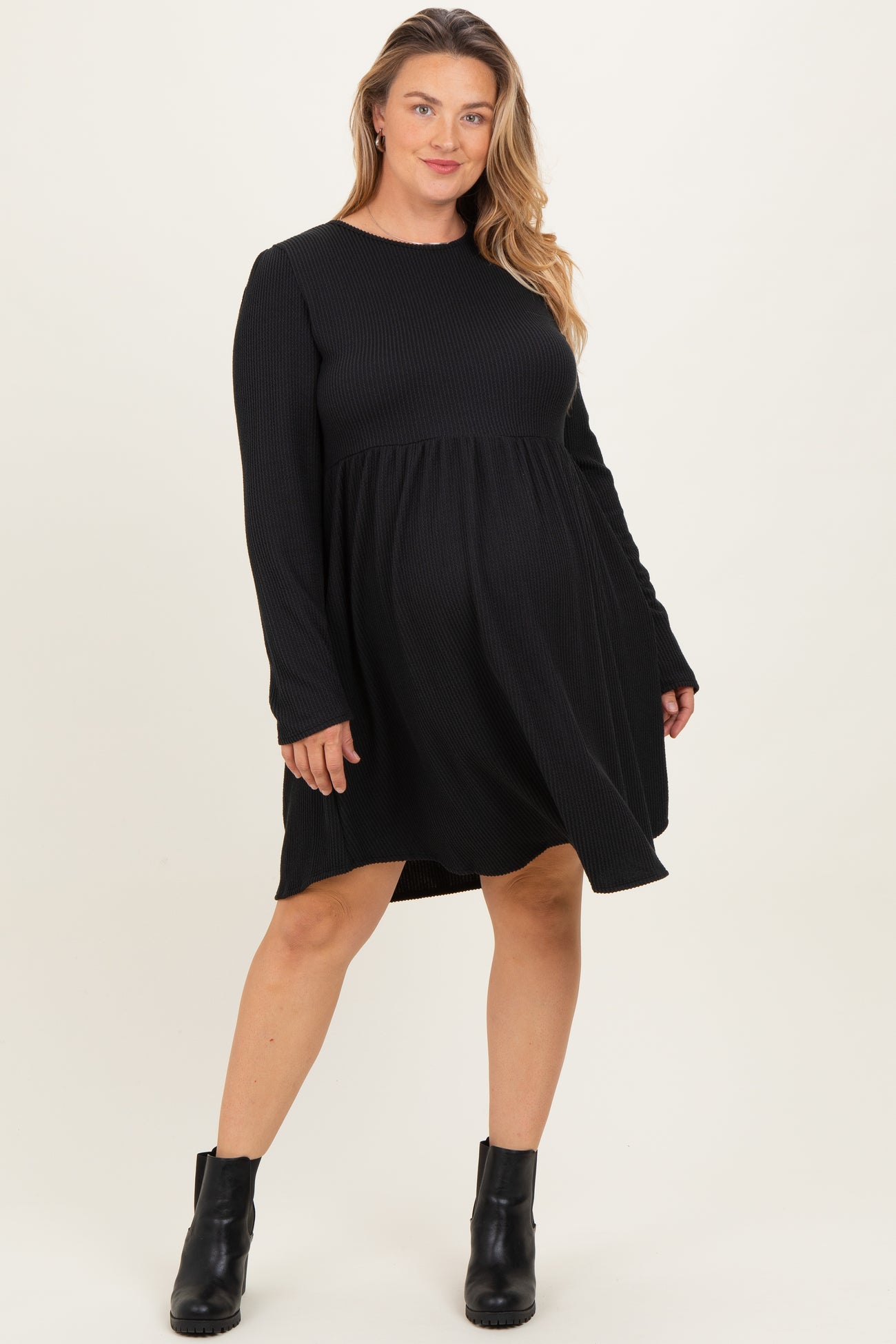 woman wearing a black long sleeve maternity dress with a swing silhouette, showcasing her baby bump