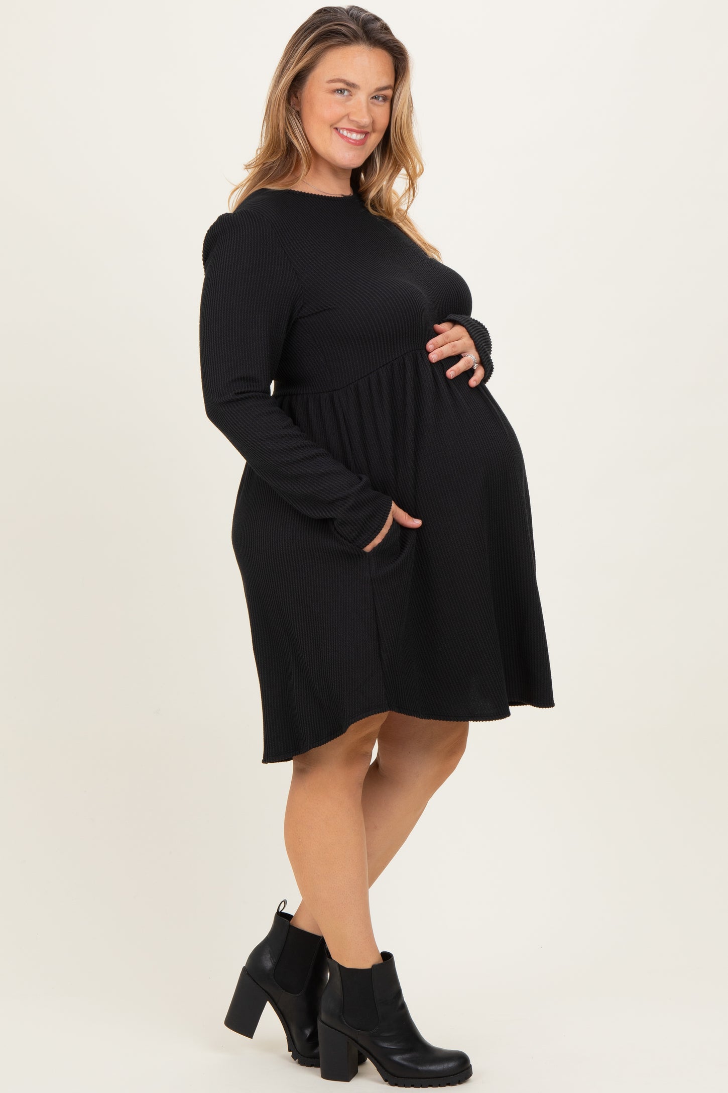woman wearing a black long sleeve maternity dress with pockets and a visible baby bump