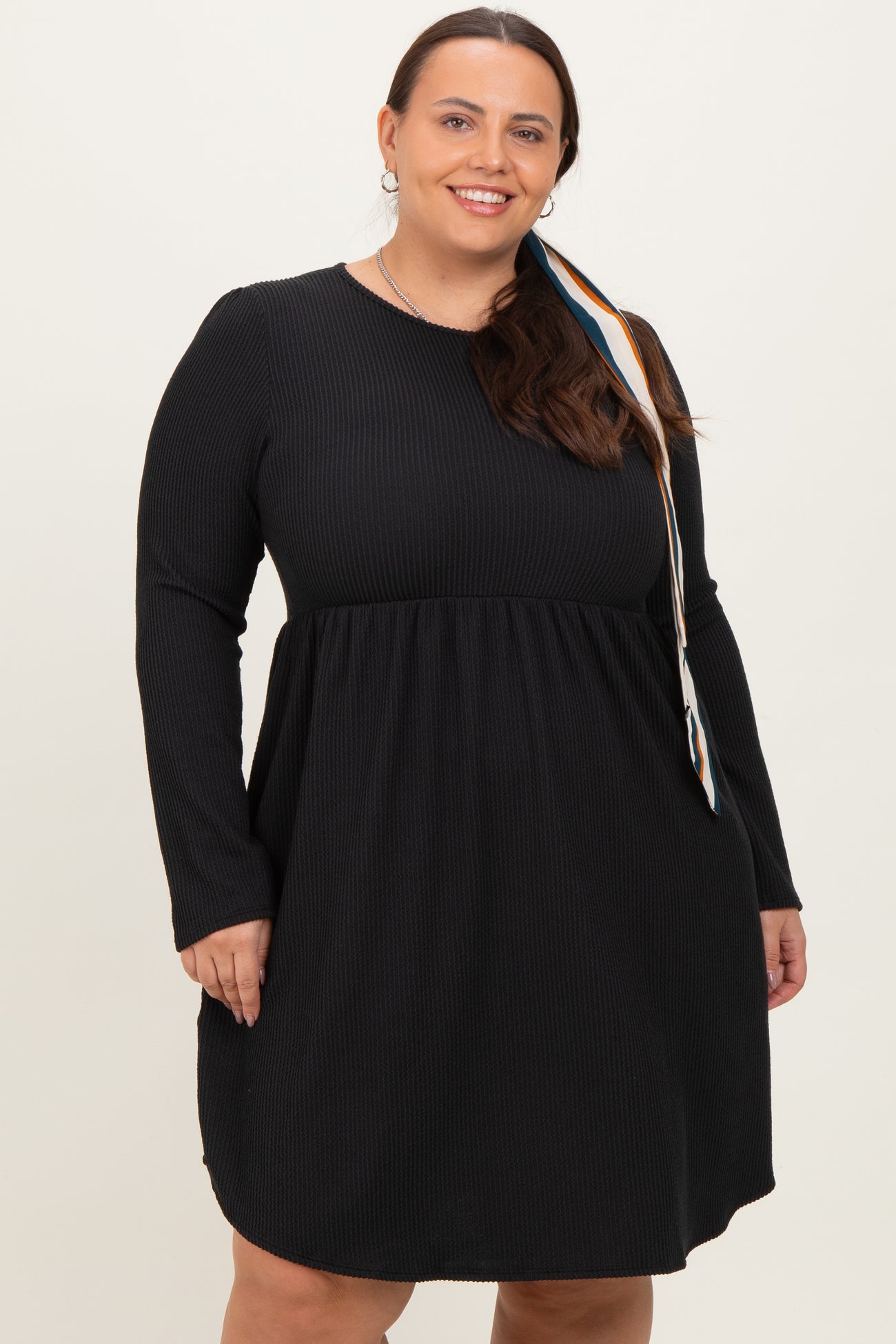 woman wearing a black long sleeve ribbed plus size dress with a flared skirt and round neckline