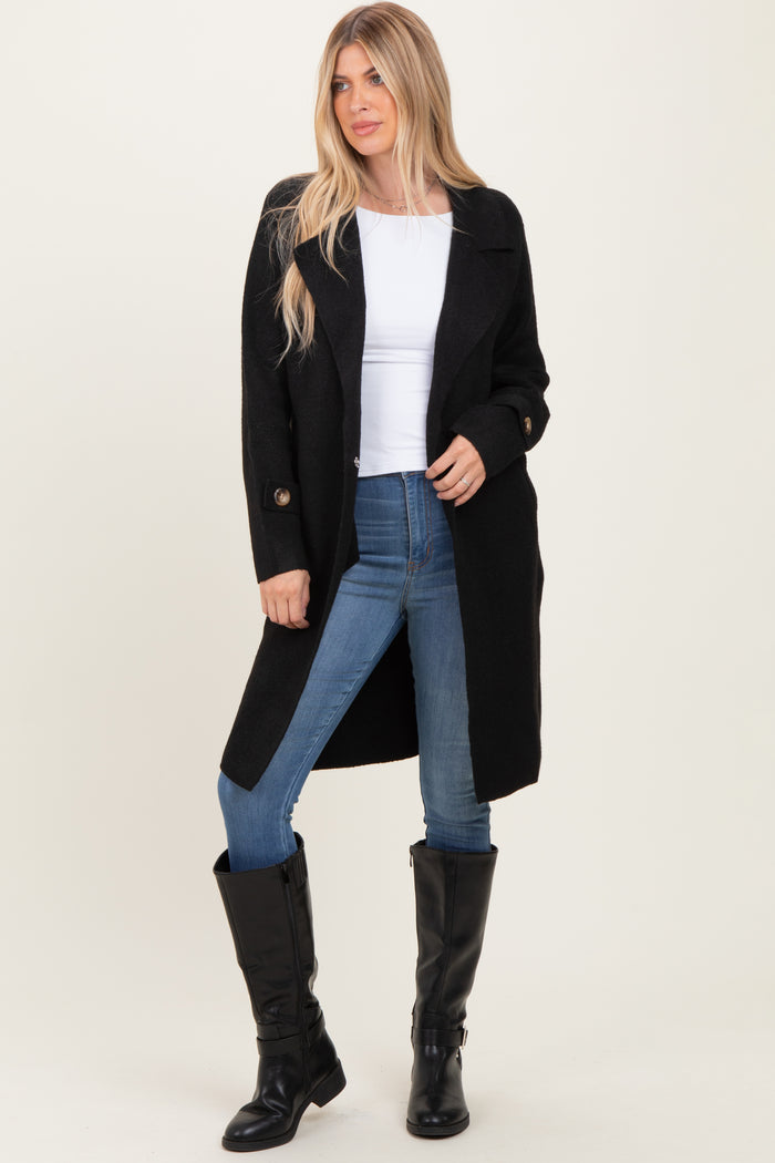 woman wearing a black long coat over a white top and blue jeans, paired with black knee-high boots