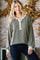 woman wearing an olive green oversized knit sweater with button details, styled with dark jeans and a casual look