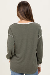 woman wearing a dark green maternity sweater with ribbed texture and light cream accents, showing her back