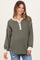 woman wearing a green ribbed maternity top with cream buttons and long sleeves, showing her baby bump