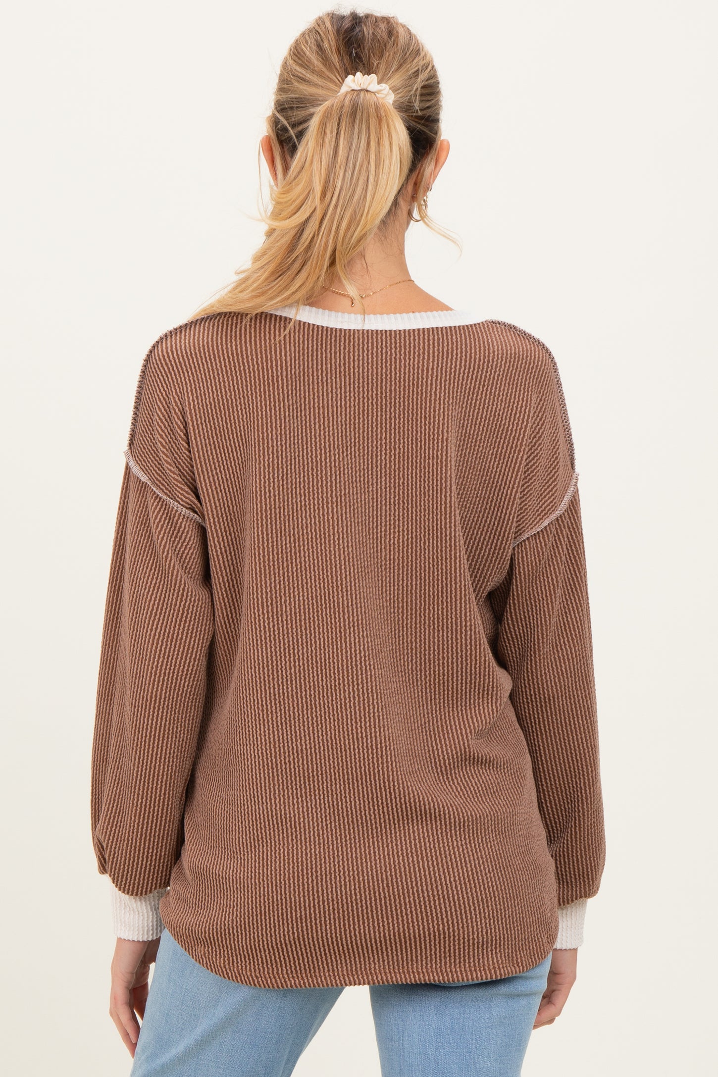 woman wearing a brown ribbed maternity sweater with white accents, viewed from the back