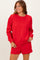 woman wearing a red oversized sweatshirt with long sleeves and a crew neckline, paired with matching shorts