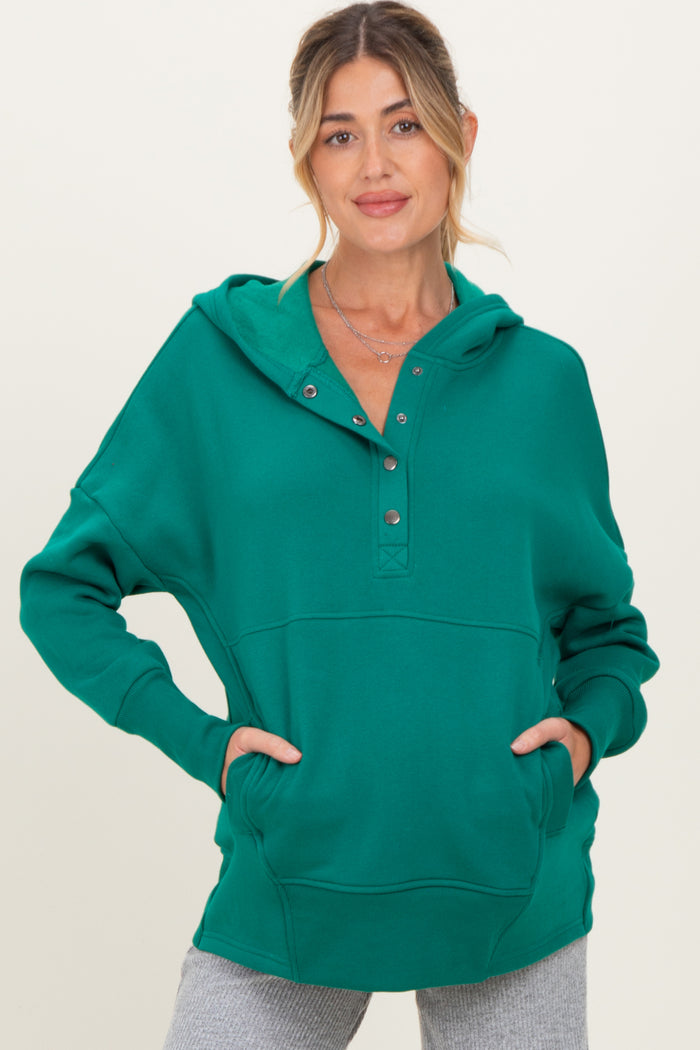 woman wearing a green maternity hoodie with a buttoned placket and front pockets