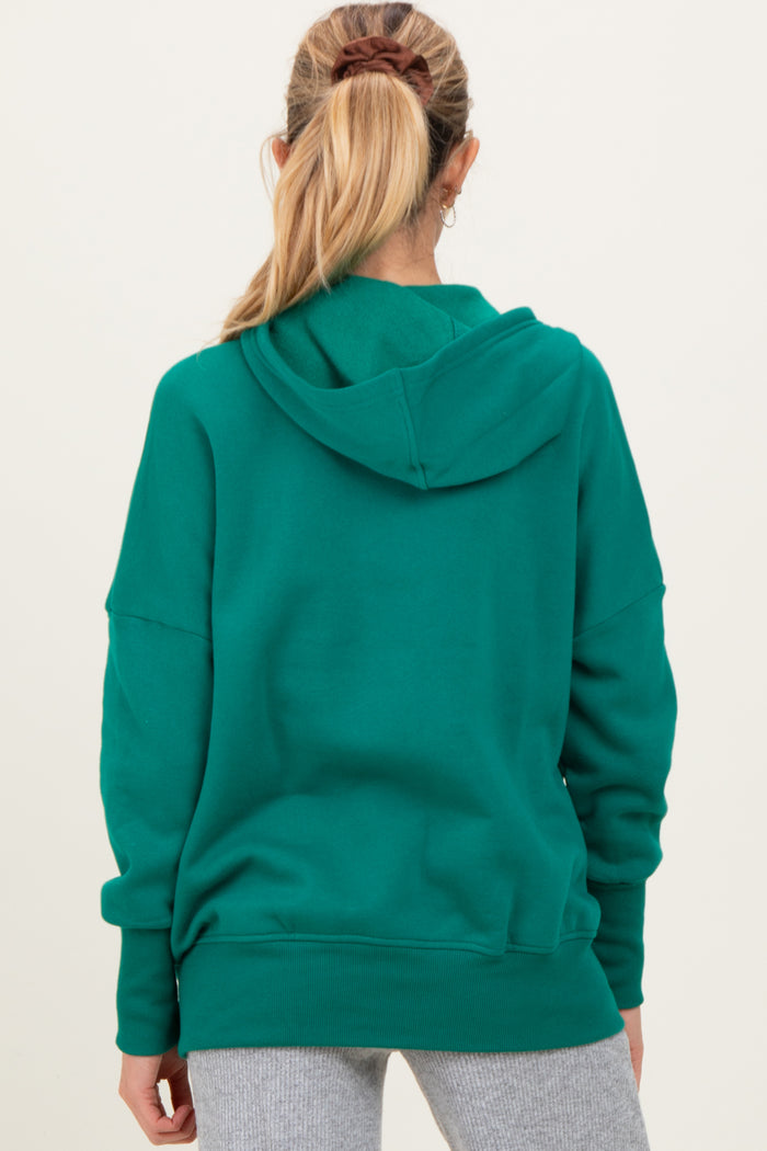 woman wearing a green maternity hoodie with a relaxed fit and hood, viewed from the back