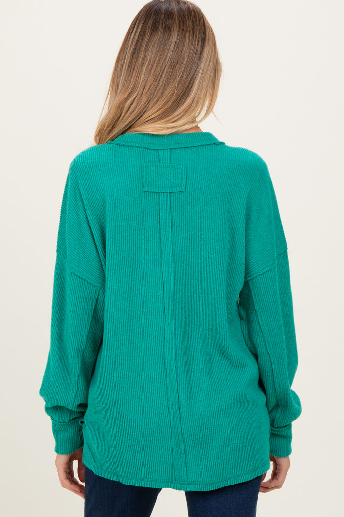 woman wearing a teal oversized ribbed maternity sweater with a relaxed fit and drop shoulder design