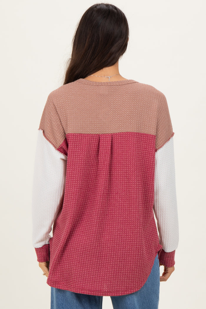 woman wearing a color block long sleeve top in mauve, white, and rose from the back, featuring a relaxed fit
