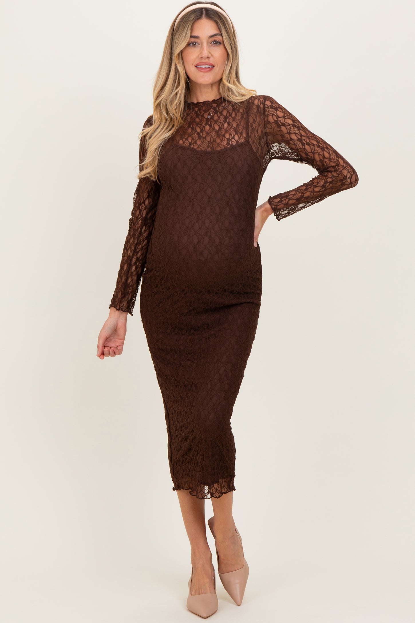 woman wearing a brown lace long sleeve maternity dress that fits snugly over her baby bump