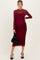 woman wearing a burgundy lace maternity dress with long sleeves and a fitted silhouette, holding a black handbag and showing a baby bump