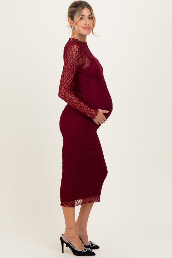 woman wearing a burgundy lace maternity dress with long sleeves and a fitted silhouette showing her baby bump