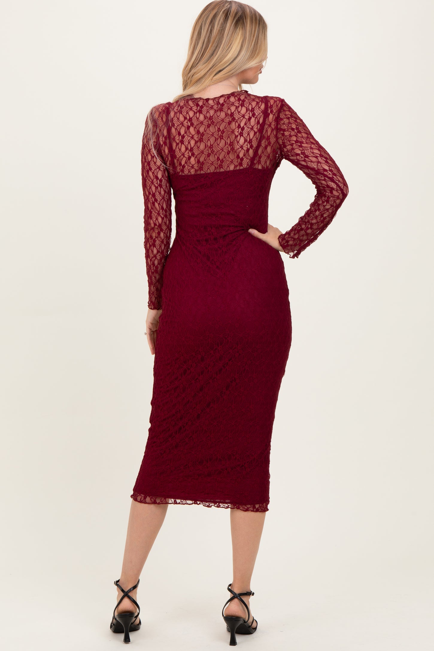 woman wearing a burgundy lace long sleeve midi dress with a fitted silhouette and back view