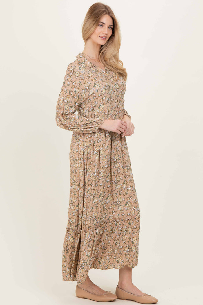woman wearing a beige floral long sleeve maxi dress with a gathered waist and tiered skirt
