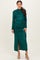 woman wearing a dark green long sleeve glitter dress with side ruching and a front slit, posing elegantly