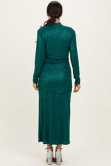 woman wearing a dark green long sleeve glittery maxi dress, view from the back showing ruching details