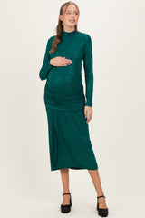 woman wearing a green sequined maternity dress with long sleeves and ruched details, holding her baby bump
