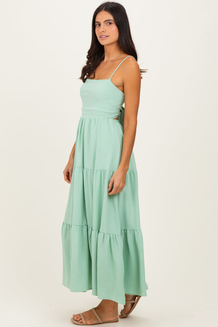 woman wearing a mint green maxi dress with tiered layers and thin straps
