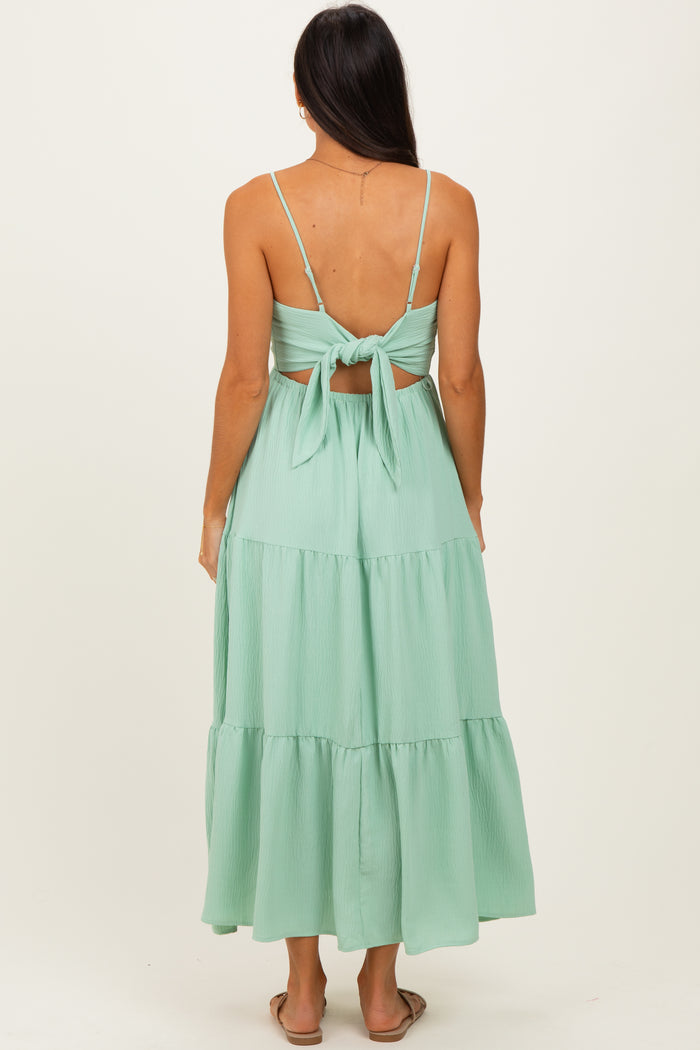 woman wearing a mint green tiered maxi dress with thin straps and a tied back detail