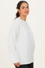 woman wearing a white cable knit sweater with long sleeves and a relaxed fit